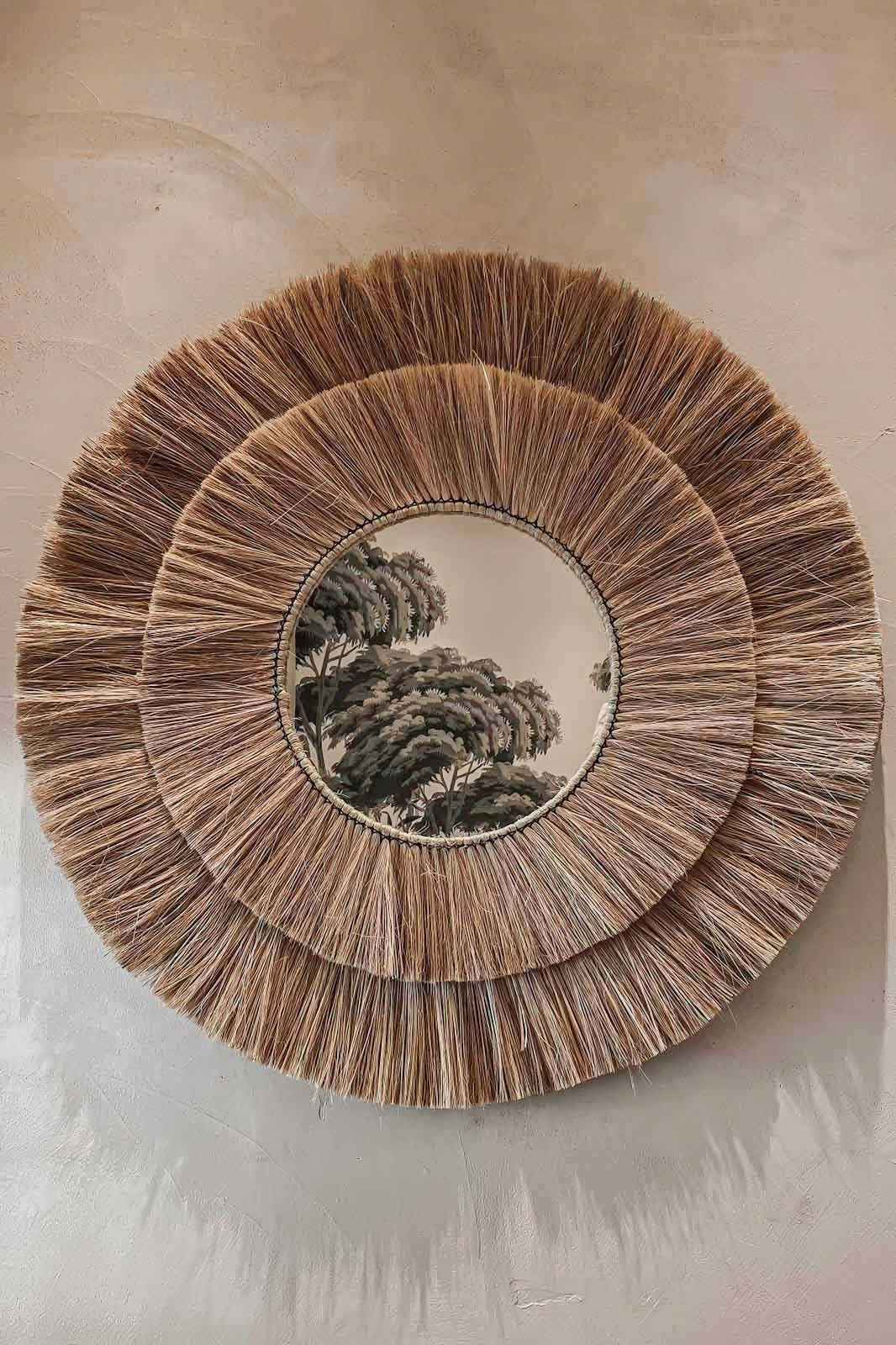 Miroir rond en fibres naturelles dans l’entrée d’une villa provençale modernisée à Mougins, avec mur en enduit à la chaux et ambiance méditerranéenne aux accents artisanaux